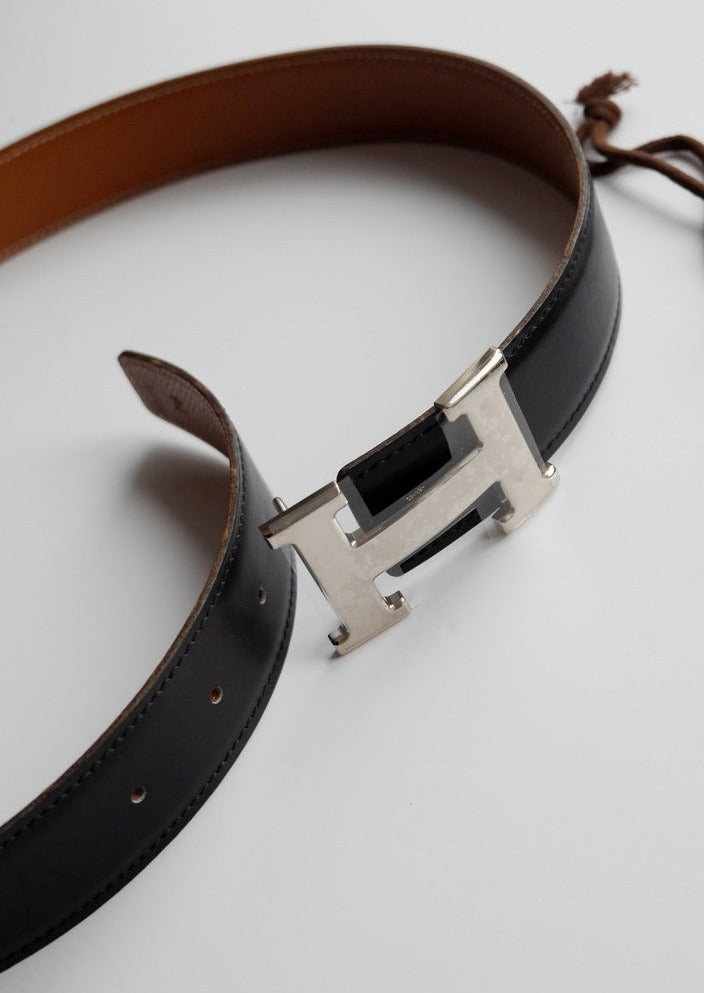 Authentique ceinture Hermes Constance H réversible en cuir noir/marron d'occasion SHW