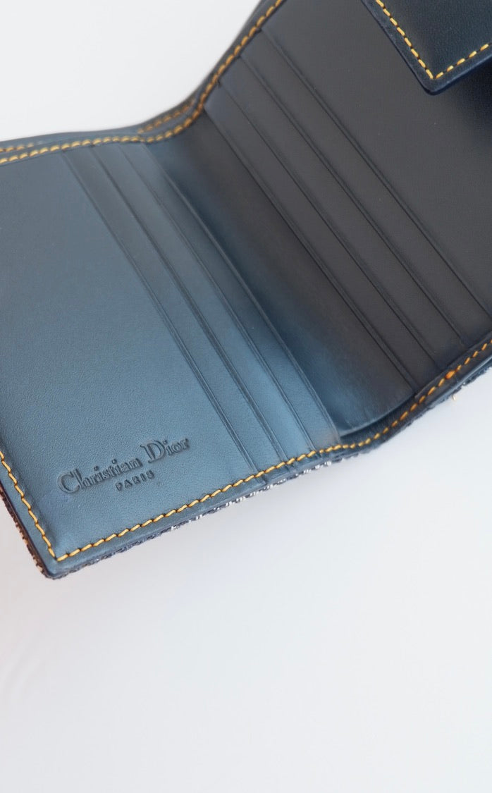 Portefeuille Dior authentique d'occasion, plié en deux, bleu marine, avec breloque D, motif Oblique.