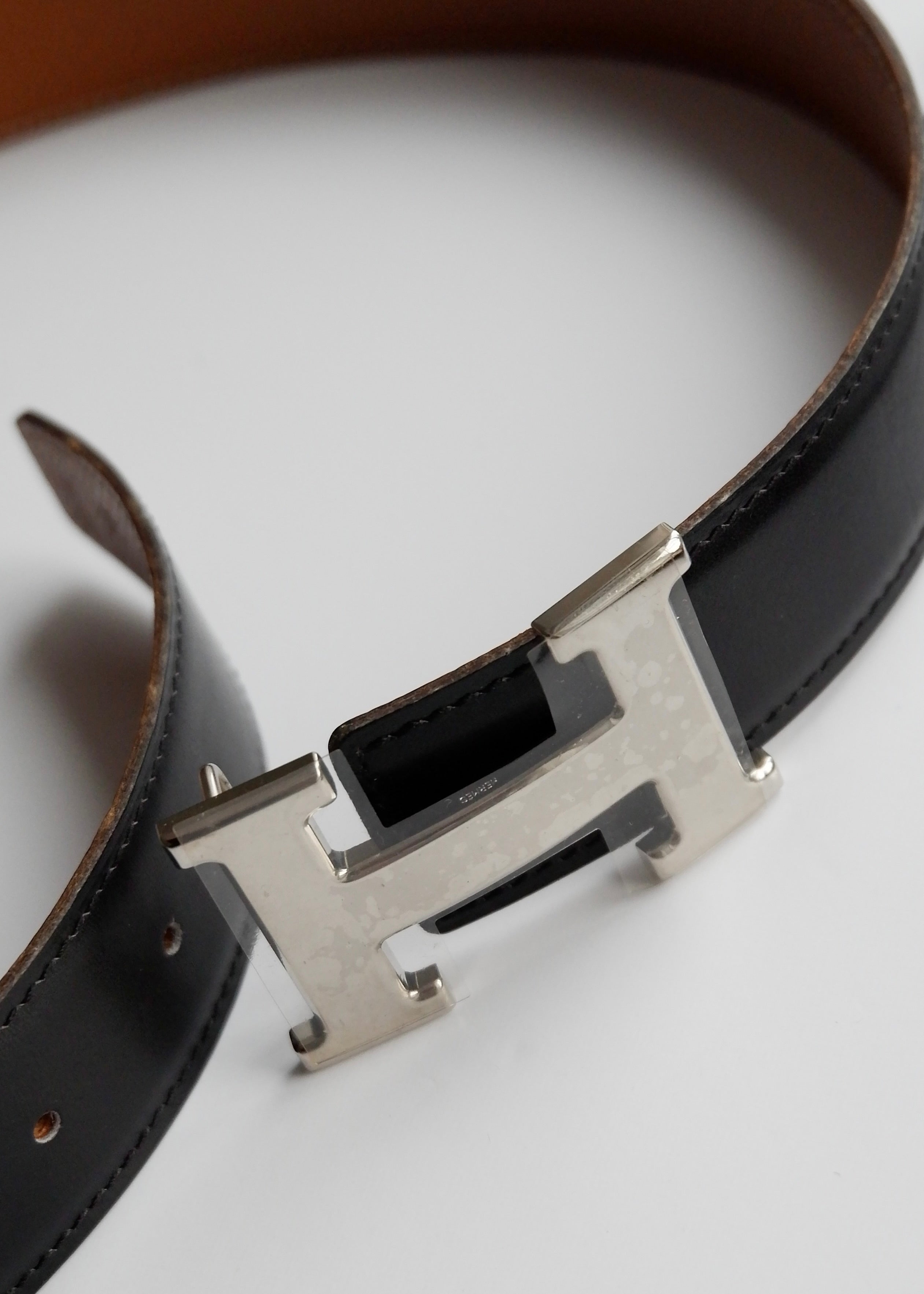 Authentique ceinture Hermes Constance H réversible en cuir noir/marron d'occasion SHW