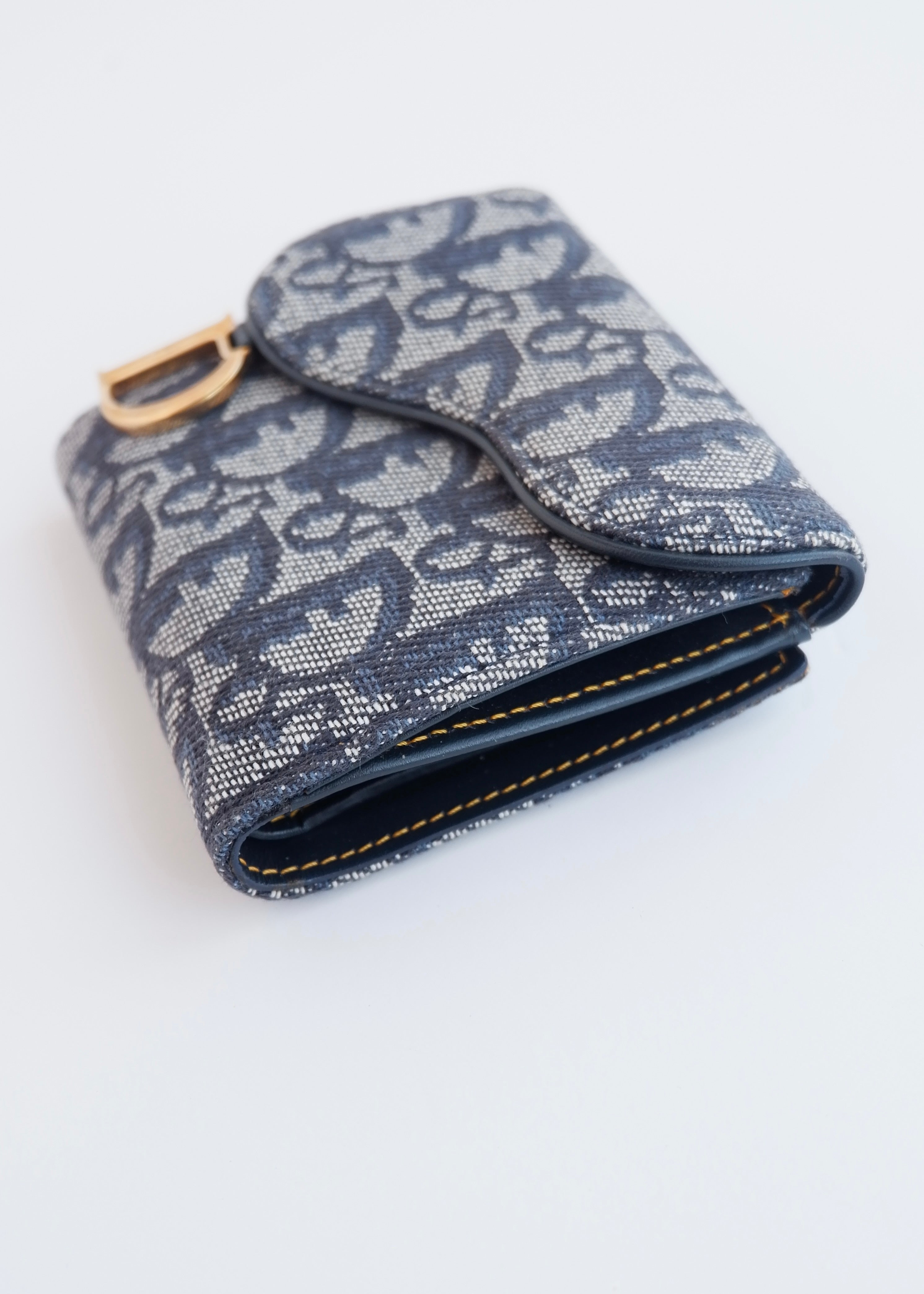 Portefeuille Dior authentique d'occasion, plié en deux, bleu marine, avec breloque D, motif Oblique.